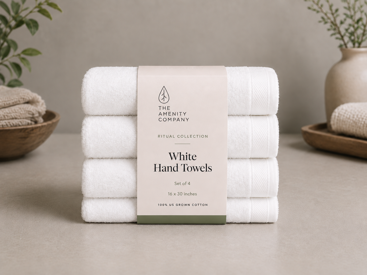 Stack of four white hand towels with a Ritual Collection belly band